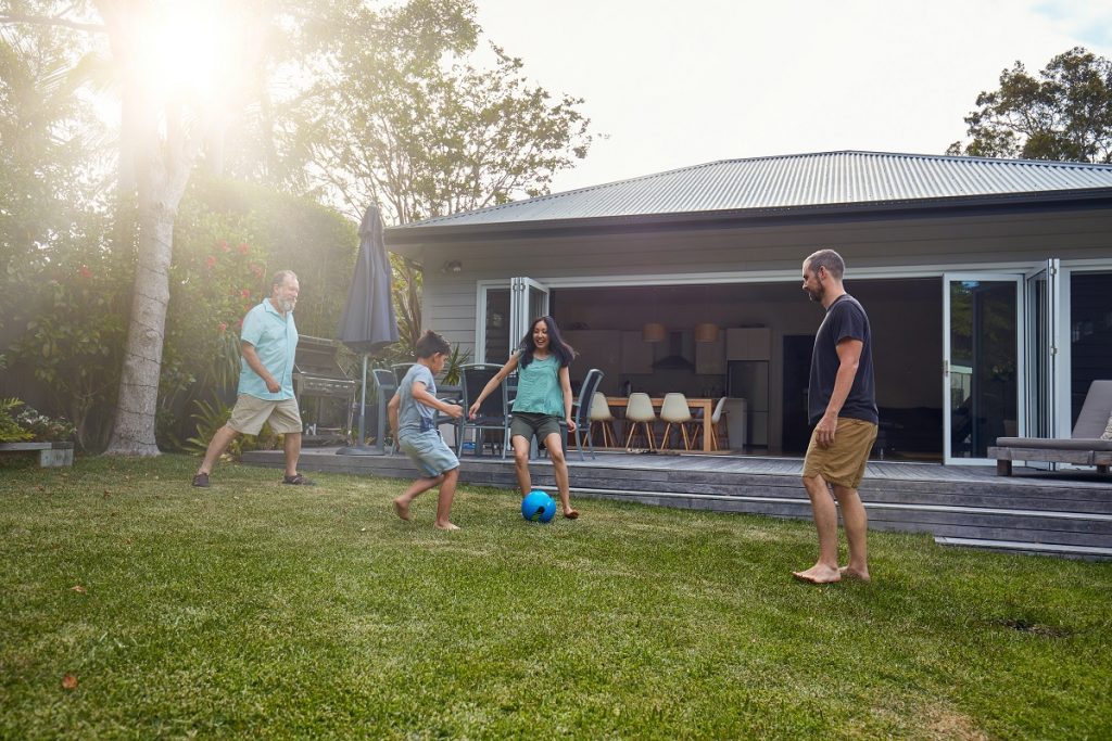 multi-generation-family-playing-soccer-on-lawn