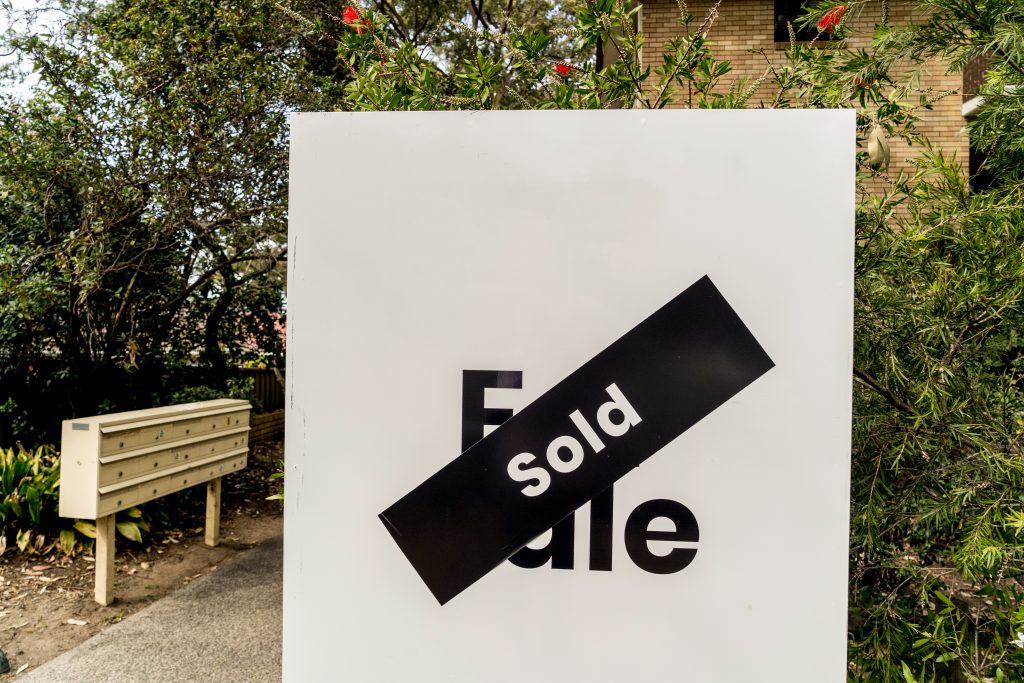 white-for-sale-sign-near-the-resedential-appartment-building-with-sold-sticker-on-it-real-estate-property-investment-boom-concept
